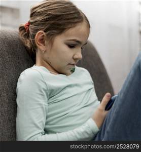 little girl playing smartphone indoors