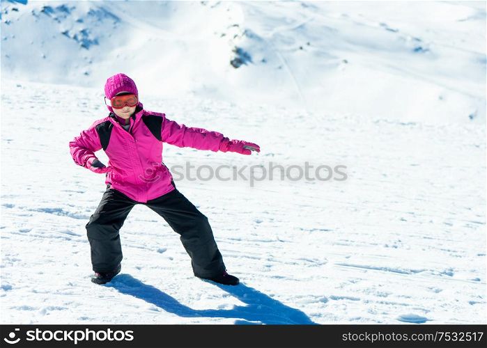Little girl playing snowboard trainer on snow at Sierra Nevada ski resort wearing snow clothes.. Little girl playing snowboard trainer on snow