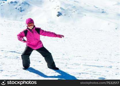 Little girl playing snowboard trainer on snow at Sierra Nevada ski resort wearing snow clothes.. Little girl playing snowboard trainer on snow