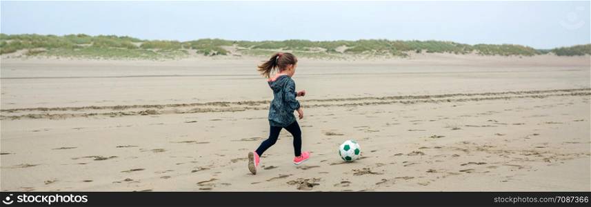 Little girl playing soccer on the beach in autumn. Little girl playing soccer on the beach
