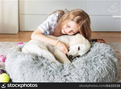 Little girl playing with a golden retriever puppy at home. Friends at home.