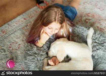 Little girl playing with a golden retriever puppy at home. Friends at home.
