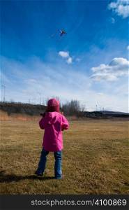 Little girl playing with a kite in a field