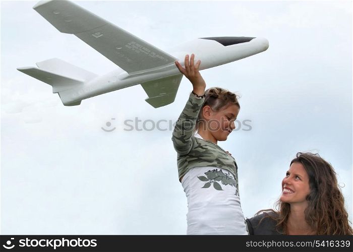 little girl playing with a small scale model of plane