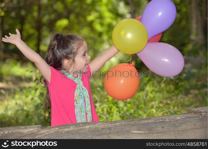 Little girl playing with balloons in forest