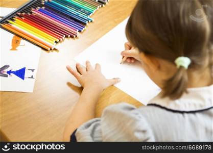 little girl playing with colors. The focus is on the hand drawing