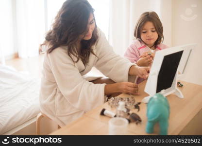 Little girl playing with her mother jewellery and make up