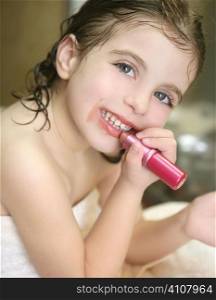 Little girl playing with lipstick makeup on the bathroom