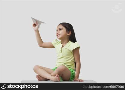Little girl playing with paper airplane isolated over gray background