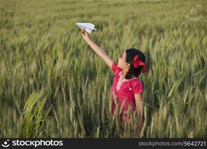 Little girl playing with paper plane in the field