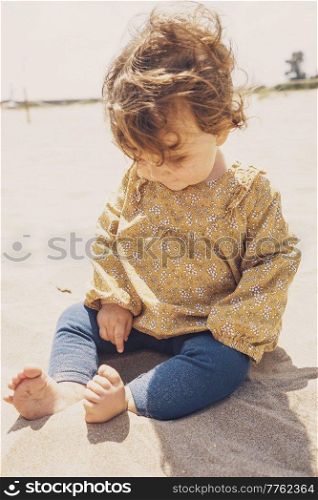 Little girl playing with sand at the beach