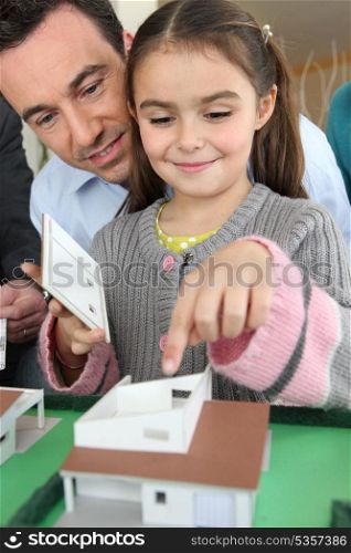 Little girl playing with scale model of housing