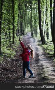 Little girl playing with stick in a forest on country road