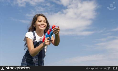 little girl playing with water gun outside