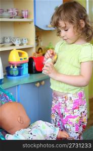 little girl plays with doll on kitchen