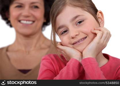 little girl posing with mother all smiles in background