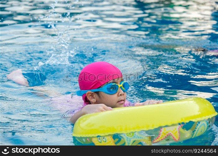 Little girl practicing swimming in the pool. Happy children swimming and playing in the water. summer vacation concept.