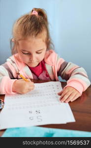 Little girl preschooler learning to write letters at school. Kid writing letters doing a school work. Concept of early education