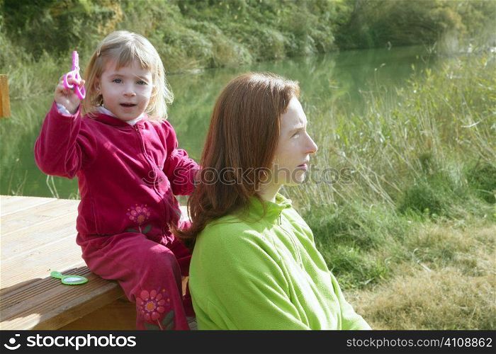 Little girl pretending be hairdresser with her mother