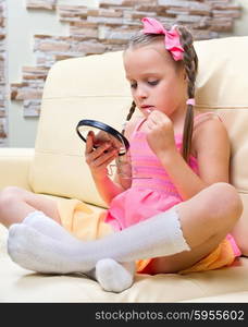 Little girl puts makeup on sofa