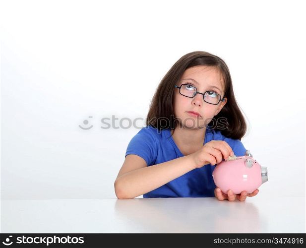Little girl putting coin in piggybank