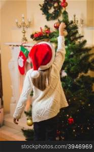 Little girl putting decorative ball on Christmas tree