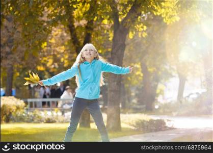 Little Girl Raising her Arms and Enjoying a Sunny Autumn Day in Park