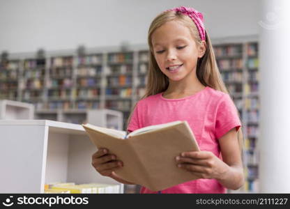 little girl reading book library