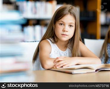 Little girl reading books in library. I love reading