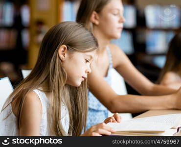 Little girl reading books in library. I love reading