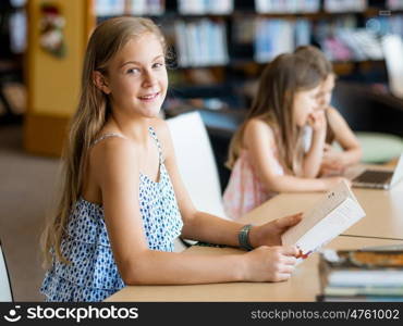 Little girl reading books in library. I love reading