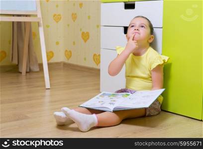 Little girl reading box in a home (book are unrecognizable)