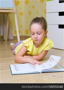 Little girl reads book on the floor