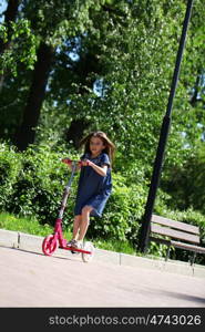 Little girl ride the scooter in the park