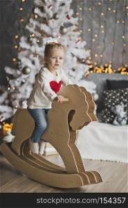 Little girl riding a toy horse.. Portrait of a child on paper horse in front of the tree 7075.