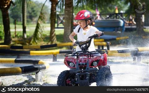 Little girl riding ATV quad bike in race track .