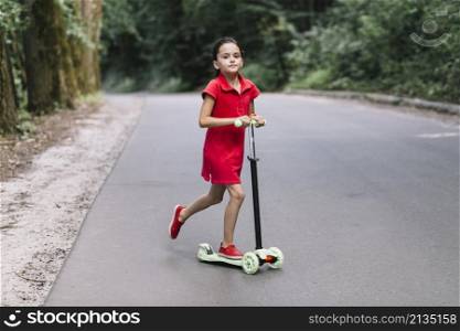 little girl riding push scooter road