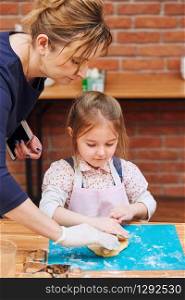 Little girl rolling the dough with her moms help for the cake. Kid taking part in baking workshop. Baking classes for children, aspiring little chefs. Learning to cook. Combining and stirring prepared ingredients. Real people, authentic situations