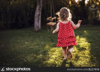 little girl running at sunset through the grass