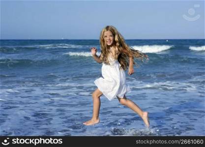 Little girl running beach shore splashing water in blue sea
