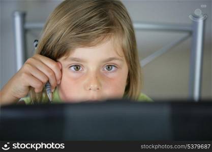 Little girl sat at the kitchen table with laptop