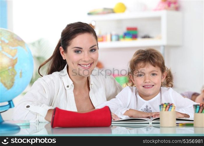 Little girl sat with teacher in class room