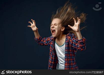 Little girl screams in studio, developing hairstyle effect. Children and wind, kid isolated on dark background, child emotion. Little kid screams in studio, developing hairstyle