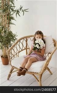 little girl sitting armchair with bouquet spring flowers