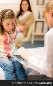 Little girl sitting at medical office pediatrician looking at document