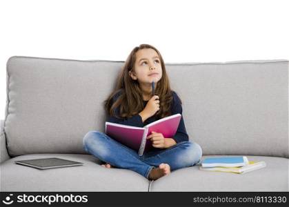 Little girl sitting on a couch and studying