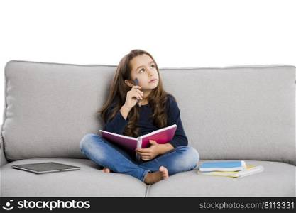 Little girl sitting on a couch and studying