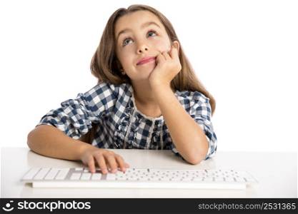 Little girl sitting on a desk and working with a computer