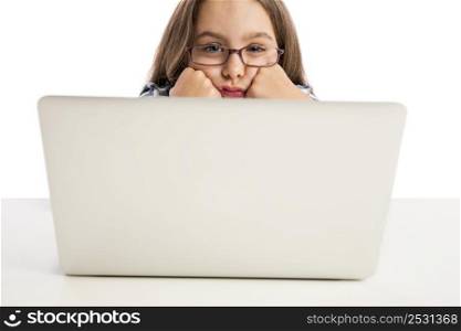 Little girl sitting on a desk and working with a laptop
