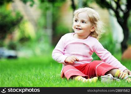 little girl sitting on green grass